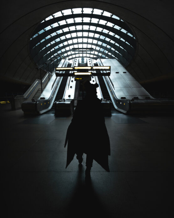 Ragazza con giaccone lungo cammina verso di me mentre sto scattando, in una situazione cinematografica nella metropolitana di Canary Wharf.