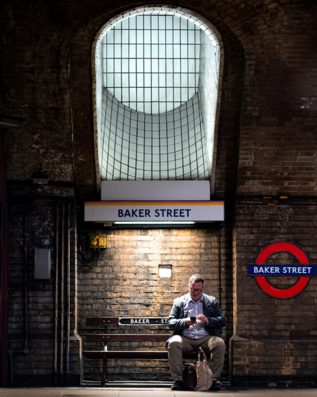 Uomo Seduto su Panchina alla Stazione Metro di Baker Street, Londra