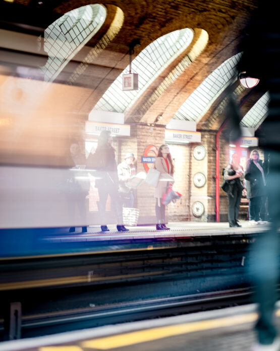 Fotografia Lunga Esposizione alla Stazione Metro di Baker Street, Londra: Incrocio di Persone a Fuoco e Treno in Movimento Sfuocato