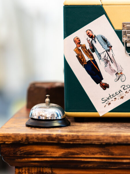 Valigia a Metà con Adesivo del Brand di un Negozio di Abbigliamento, Appoggiata su un Tavolo Accanto a un Capannello da Hotel, Un'Immagine che Rappresenta la Connessione tra Moda e Viaggio.