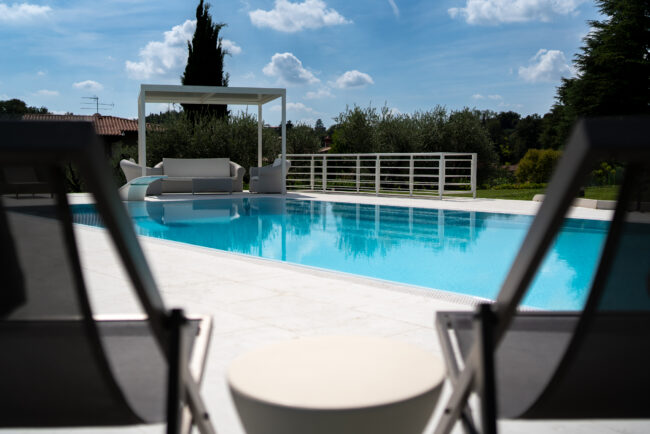 Vista di Una Grande Piscina su una Villa di Lusso, Cornice Tra Due Sdraie dal Design Elegante, Un'Atmosfera di Puro Benessere e Stile.