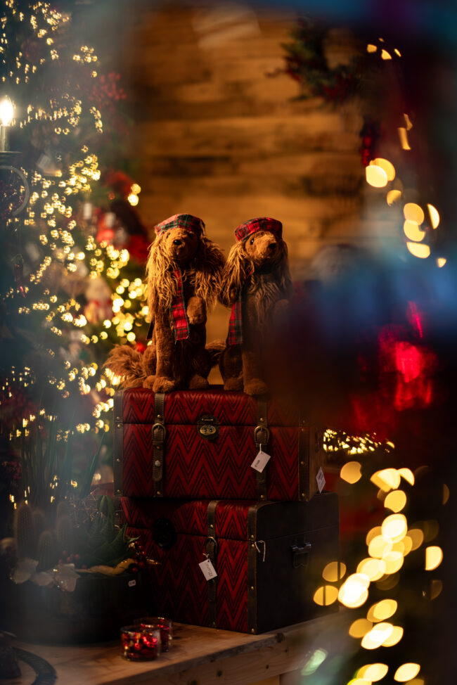 Magia Natalizia in un Negozio Luxury: Dettaglio dell'Oggettistica Natalizia con Due Cani tra Due Alberi Illuminati da Luminari Natalizi, Creando un'Atmosfera di Eleganza e Festività.