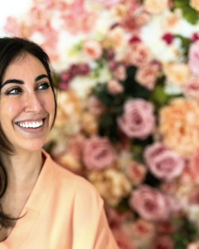 Ritratto Dottoressa Medicina Estetica: Sorridente con Sfondo Floreale Colorato