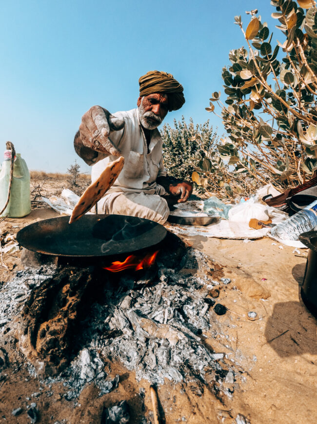 Scena Vivace nel Deserto del Thar, India: Santone Indiano Salta su una Pentola del Pane locale, Condividendo un Momento Unico con la Comunità Locale durante un Viaggio Indimenticabile."