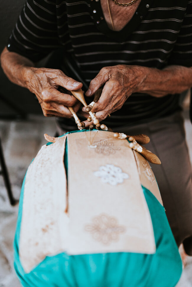 Mani Esperte al Tombolo nelle Marche: Dettaglio delle mani di una Signora che Lavora con Abilità e Passione nell'Antica Arte del Tombolo.