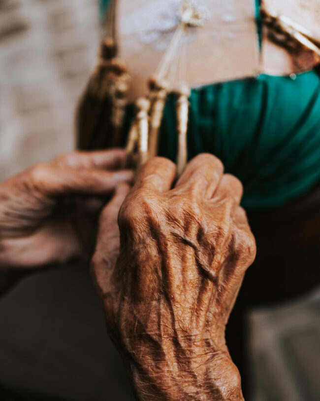 Mani Esperte al Tombolo nelle Marche: Dettaglio di mani di una Signora che Lavora con Abilità e Passione nell'Antica Arte del Tombolo.
